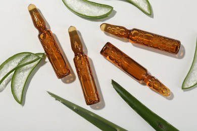 Skincare ampoules and cut aloe leaves on white background, flat lay