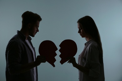 Photo of Silhouette of couple with torn paper heart on color background. Relationship problems