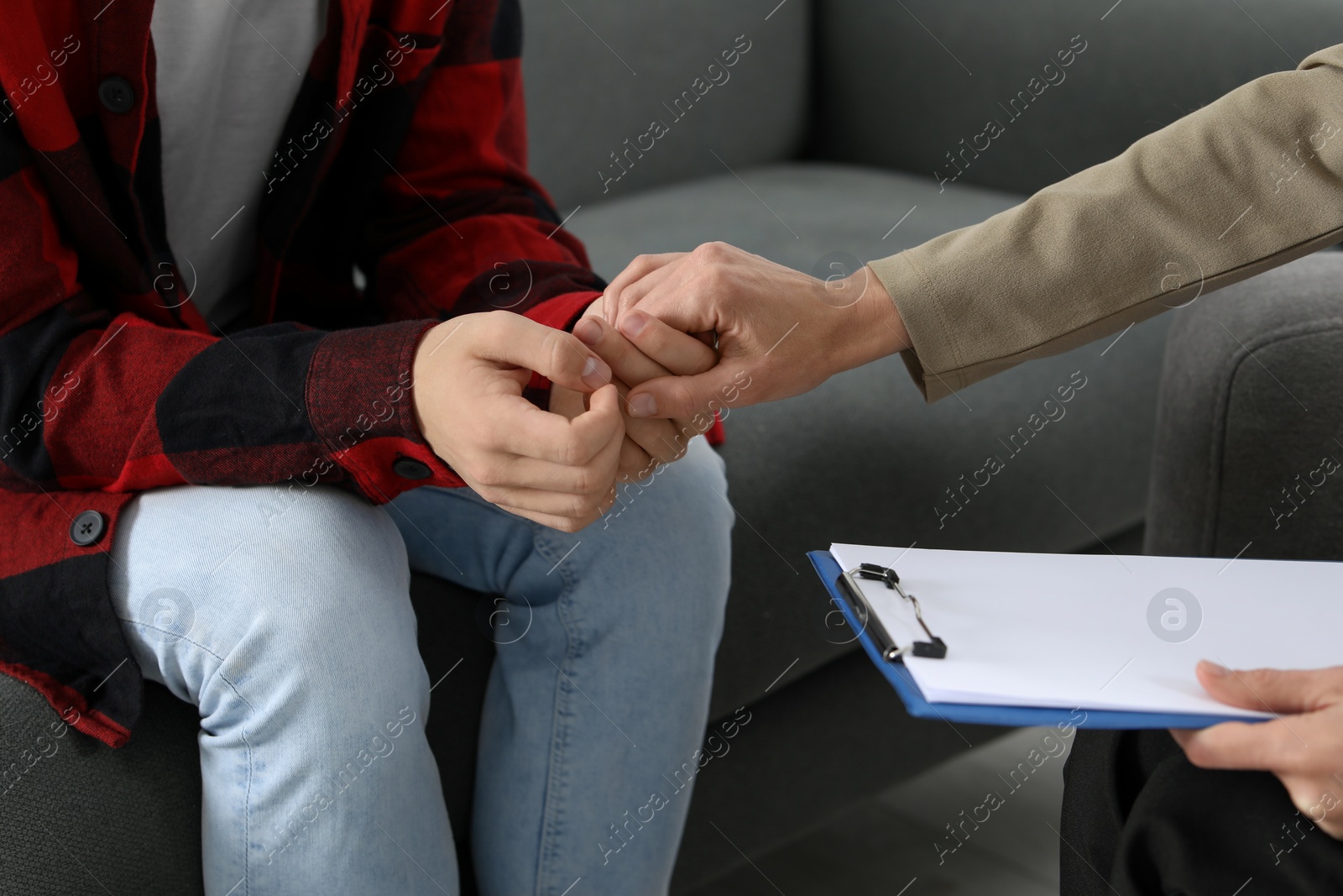 Photo of Psychologist working with teenage boy on sofa, closeup. Teenager problems