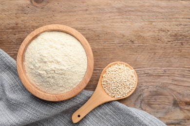 Photo of Quinoa flour in bowl and spoon with seeds on wooden table, flat lay