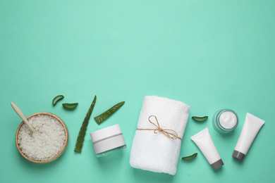 Flat lay composition with aloe vera and cosmetic products on turquoise background. Space for text