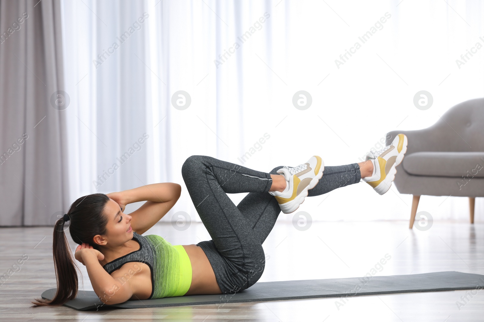 Photo of Young woman in fitness clothes doing exercise at home. Space for text