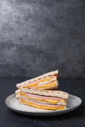 Photo of Delicious grilled sandwiches with ham and cheese on black table