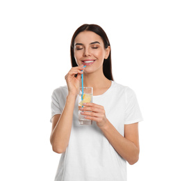 Beautiful young woman drinking tasty lemon water on white background