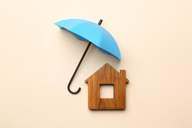 Photo of Mini umbrella and house model on beige background, flat lay