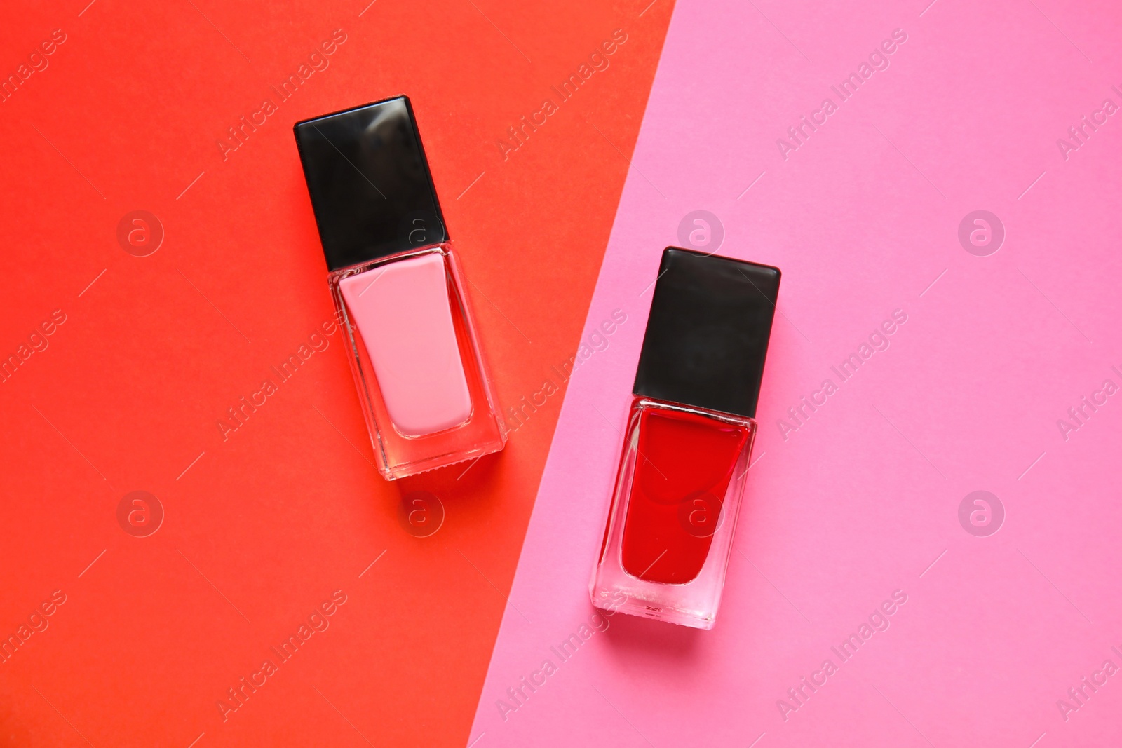 Photo of Bottles of nail polish on color background, top view