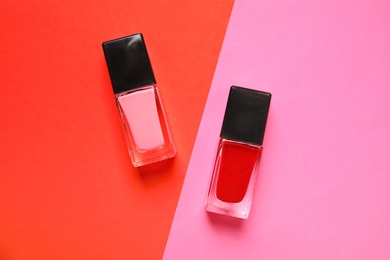 Bottles of nail polish on color background, top view