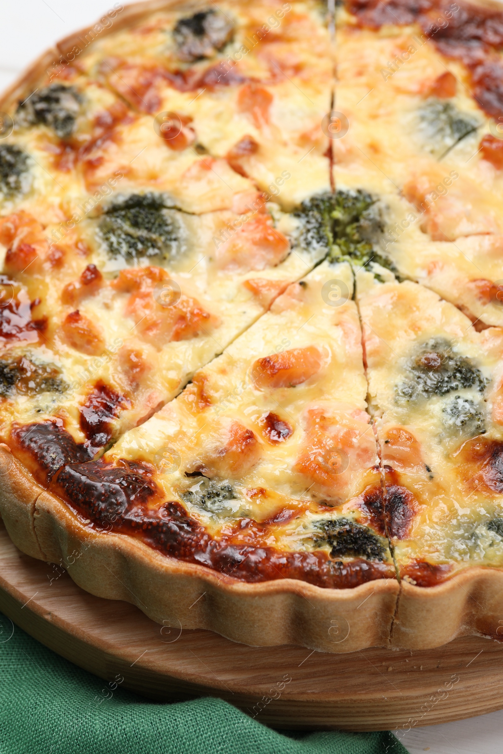 Photo of Delicious homemade quiche with salmon and broccoli on wooden board, closeup