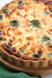 Delicious homemade quiche with salmon and broccoli on wooden board, closeup