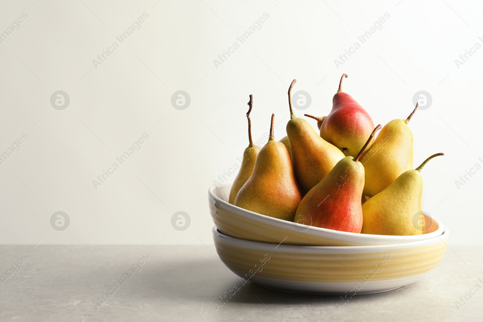 Photo of Plate with ripe pears on table against light background. Space for text