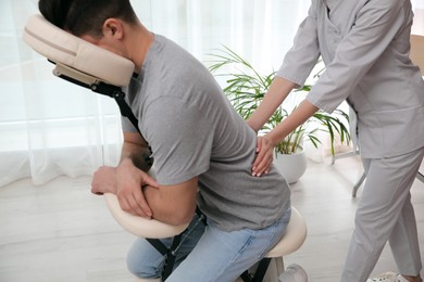 Man receiving massage in modern chair indoors