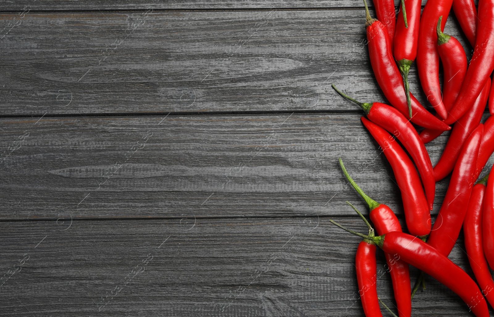 Photo of Red hot chili peppers on grey wooden table, flat lay. Space for text