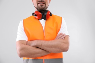 Photo of Male industrial engineer in uniform on light background, closeup. Safety equipment