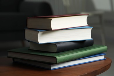 Photo of Stack of hardcover books on wooden coffee table indoors, closeup