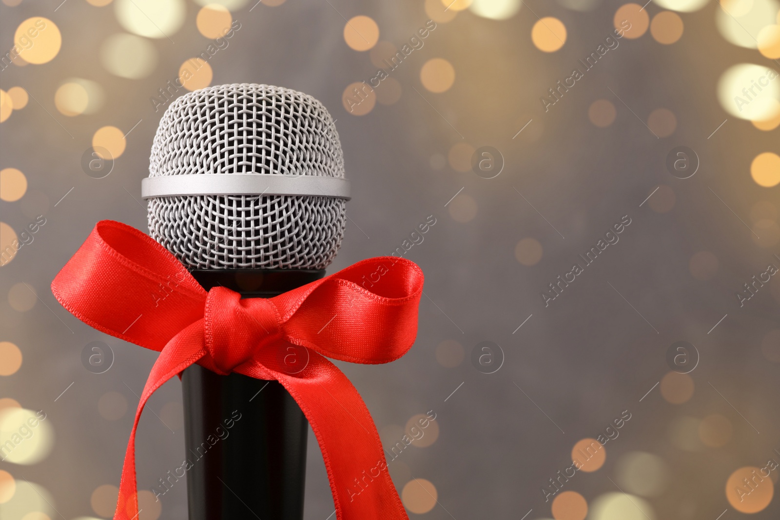 Photo of Microphone with red bow on grey background, space for text. Christmas music