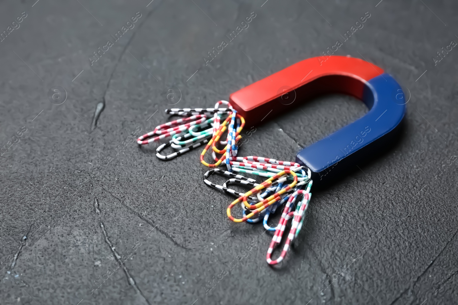 Photo of Magnet attracting paper clips on grey background, space for text