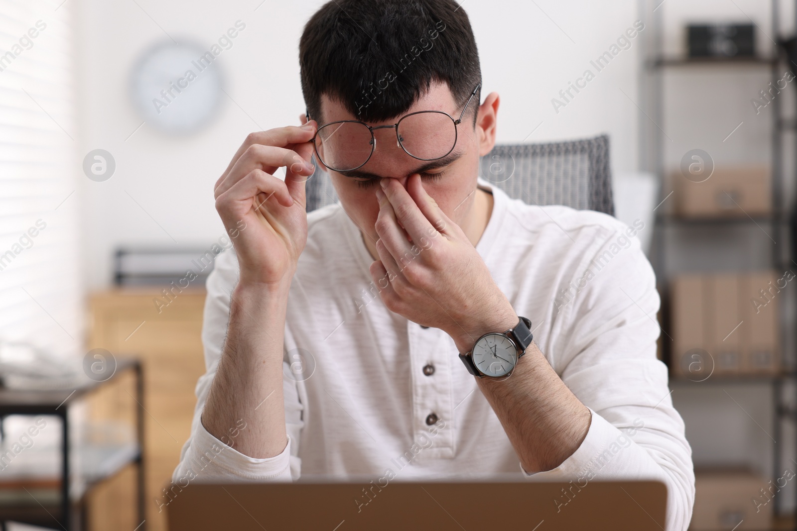 Photo of Young man suffering from headache in office