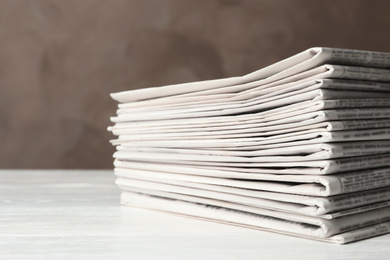 Photo of Stack of newspapers on white wooden table. Journalist's work