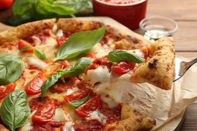 Taking piece of delicious Margherita pizza at table, closeup