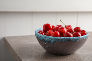 Bowl with sweet red cherries on table