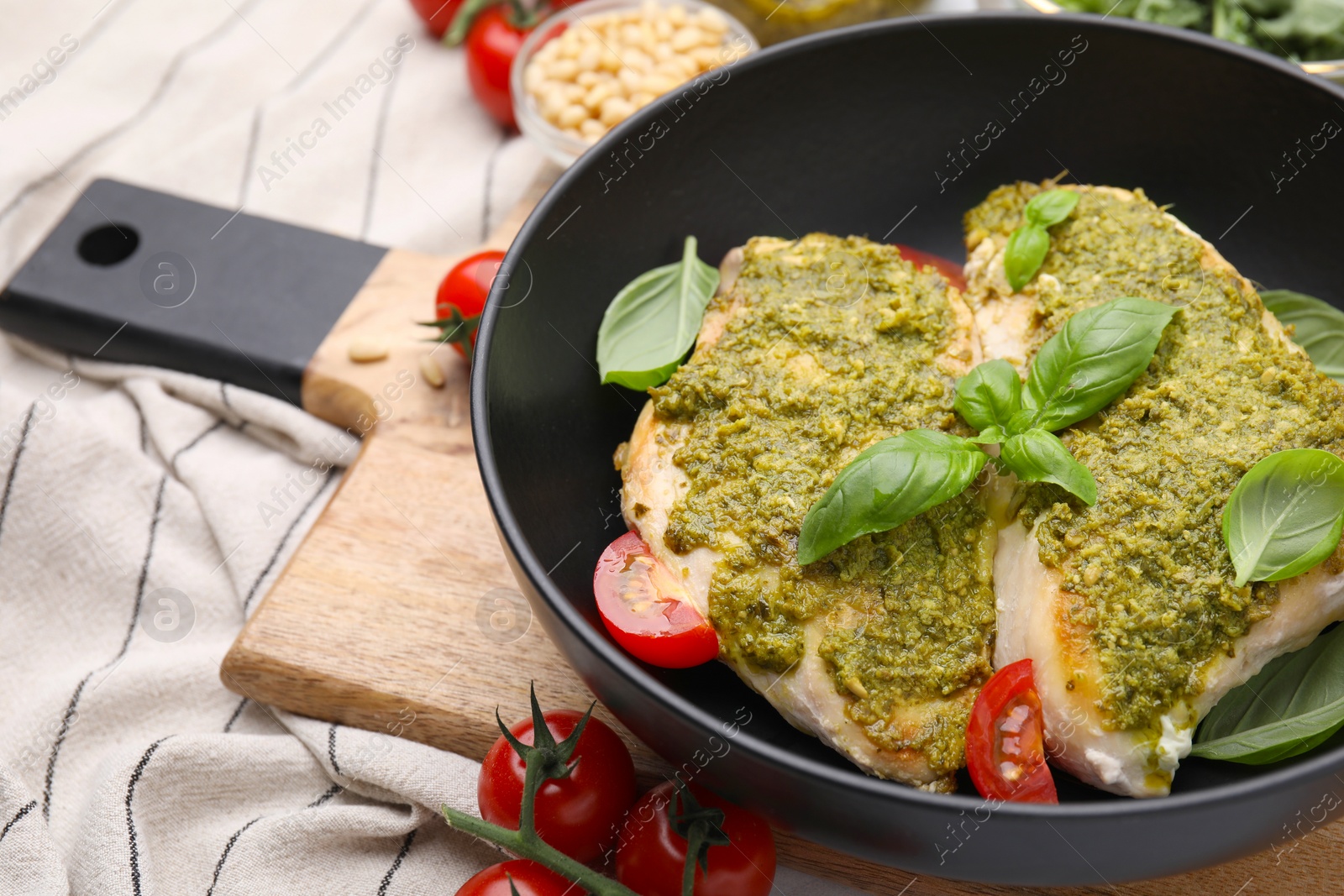 Photo of Delicious chicken breasts with pesto sauce, tomatoes and basil on table, closeup. Space for text