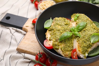 Delicious chicken breasts with pesto sauce, tomatoes and basil on table, closeup. Space for text