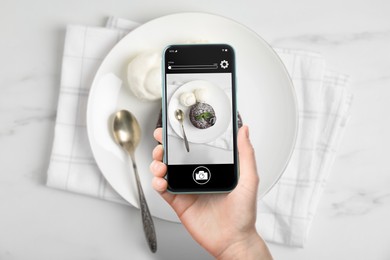Image of Woman taking picture of delicious fondant and ice cream served on white table, top view