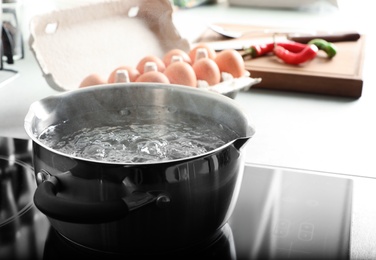 Photo of Pot with boiling water on electric stove in kitchen, space for text