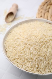 Raw rice in bowl on white table, closeup