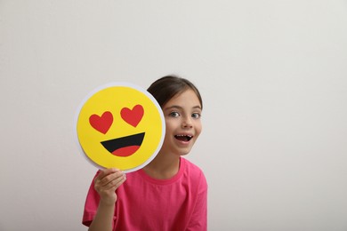 Photo of Little girl holding face with heart eyes emoji on white background