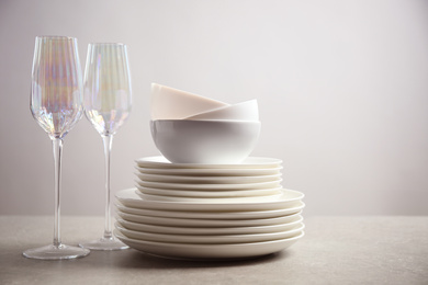 Photo of Set of clean dishes and glasses on light grey table