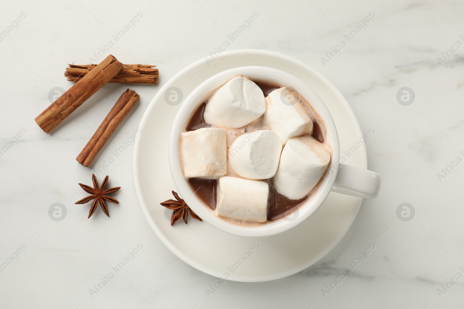 Photo of Tasty hot chocolate with marshmallows and spices on white marble table, flat lay