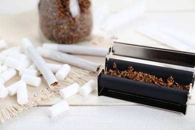 Photo of Hand rolled cigarettes, filters and tobacco on white wooden table, closeup