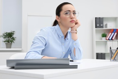 Photo of Unhappy young female intern at table in office