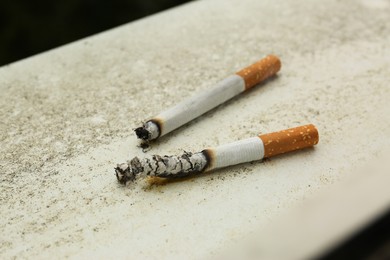 Photo of Burnt cigarettes on white textured surface, closeup. No smoking concept