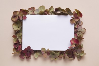 Photo of Dried hortensia flowers and sheet of paper on beige background, flat lay. Space for text