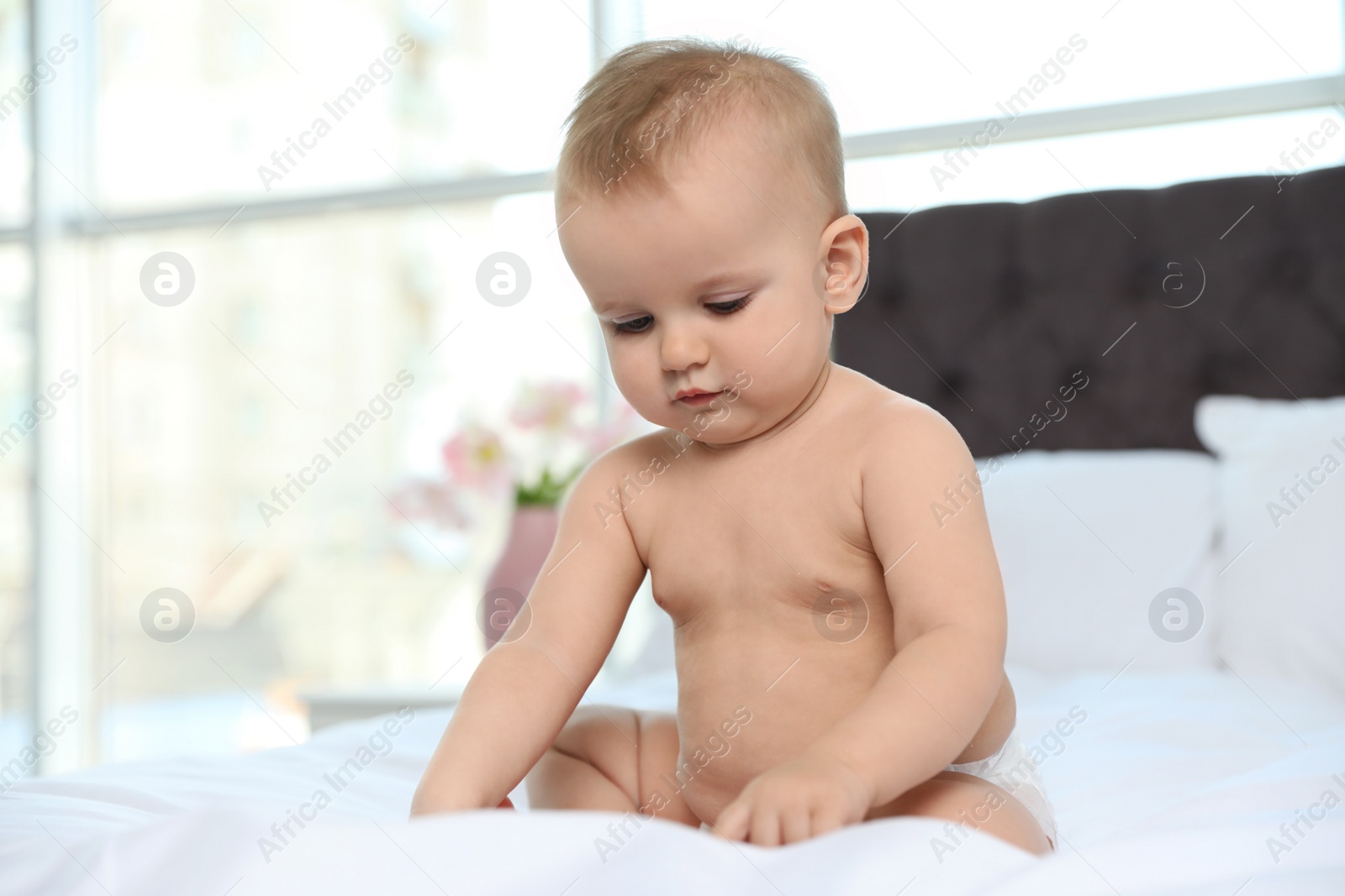 Photo of Cute baby in diaper on bed at home