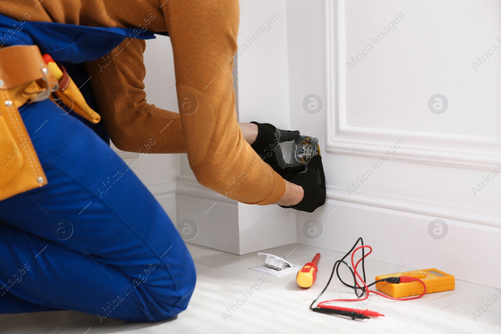 Photo of Electrician with tester checking voltage indoors, closeup