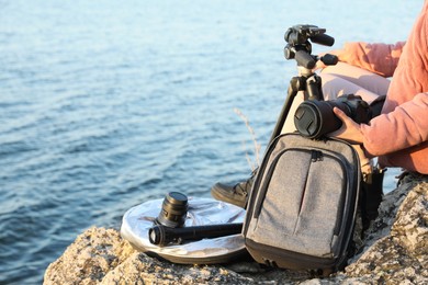 Photographer with professional equipment on rocky river coast, closeup