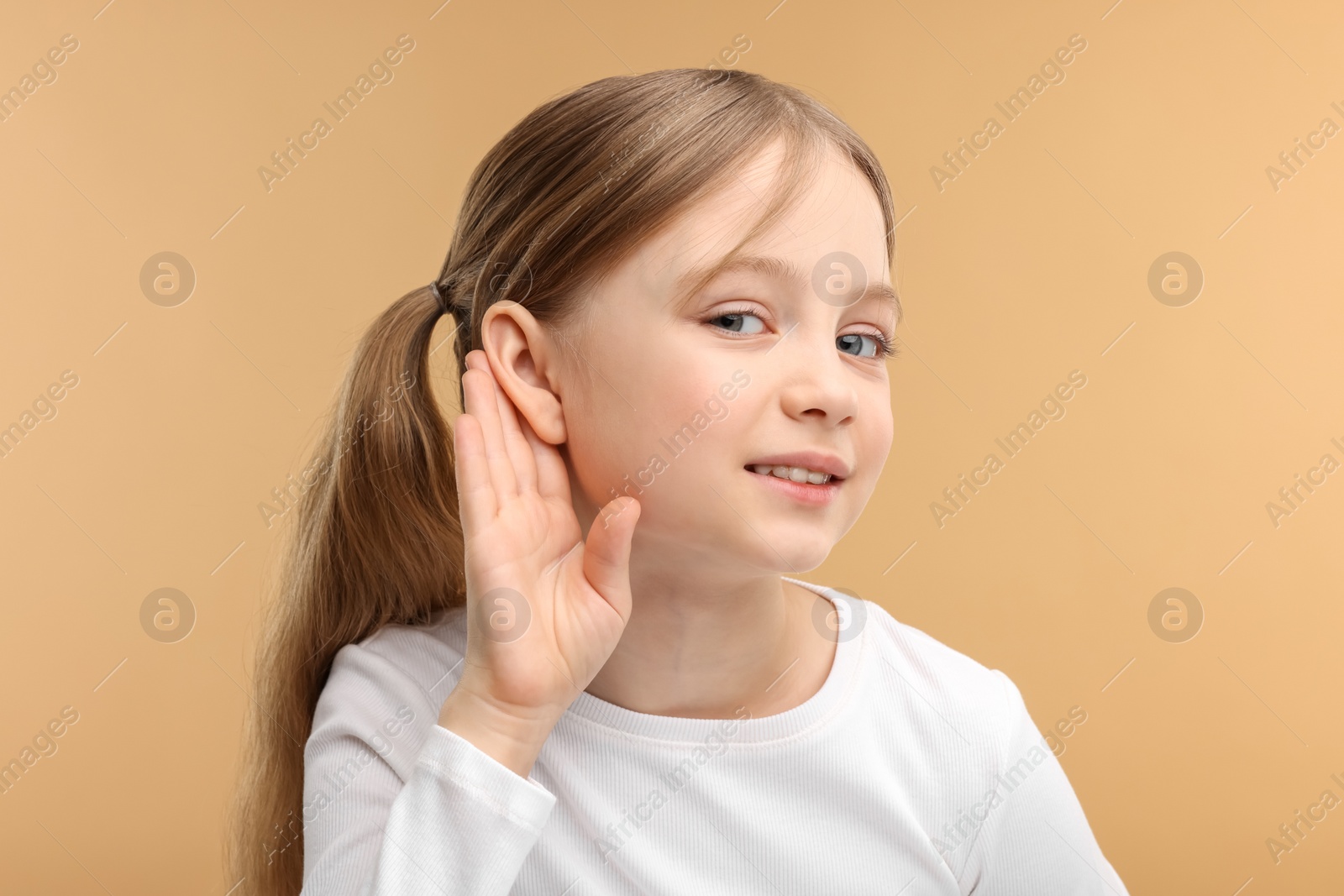 Photo of Little girl with hearing problem on pale brown background