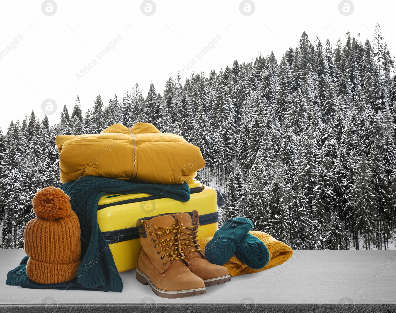 Image of Suitcase with warm clothes on stone surface against beautiful winter landscape. Space for text