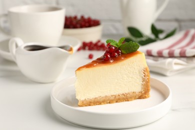 Photo of Piece of delicious caramel cheesecake with red currants and mint served on white marble table, closeup