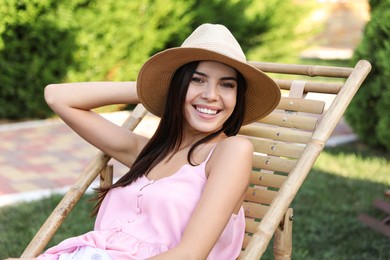 Image of Young woman resting in deck chair outdoors