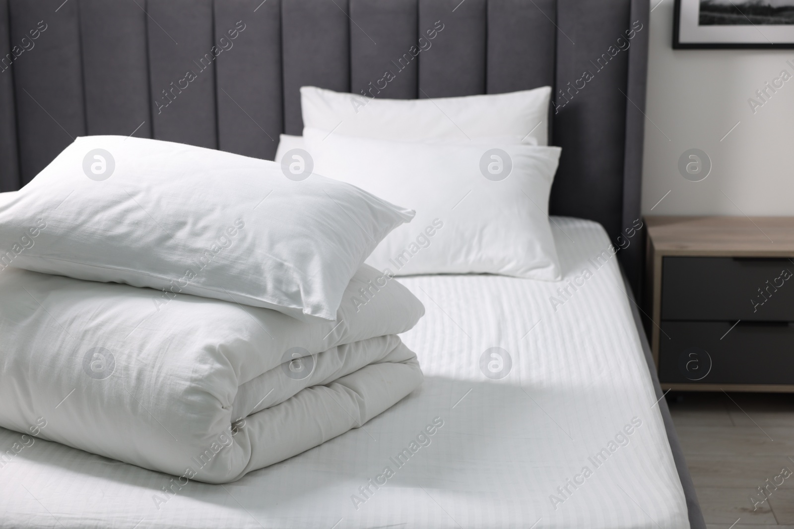 Photo of Soft white pillows and duvet on bed at home