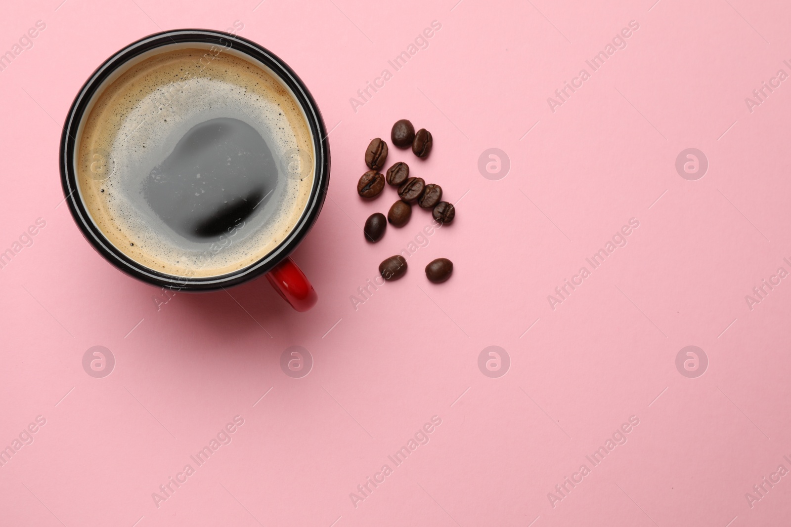Photo of Fresh coffee in cup and roasted beans on pink background, top view. Space for text