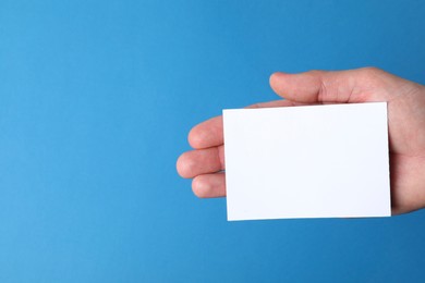 Photo of Man holding paper card on blue background, closeup. Mockup for design