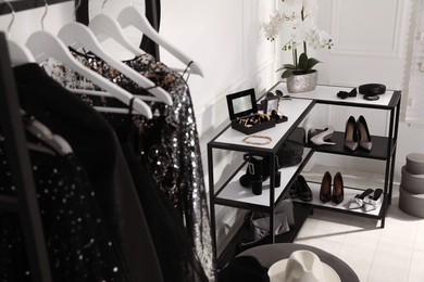 Photo of Shelving unit with stylish women's shoes, clothes and accessories in dressing room