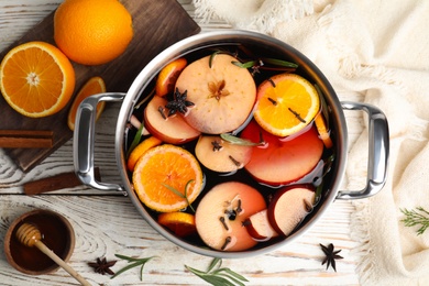 Photo of Tasty mulled wine with spices on white wooden table, flat lay