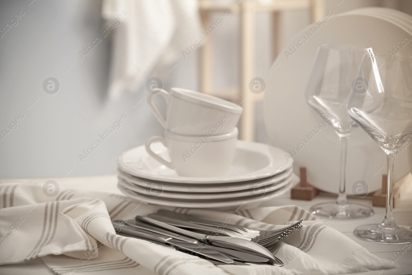 Photo of Set of clean dishware, cutlery and wineglasses on white table indoors