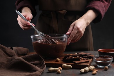 Woman with whisk mixing delicious chocolate cream at table, closeup